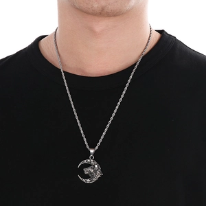 Detail of silver wolf head pendant with moon and star, worn on twisted rope chain