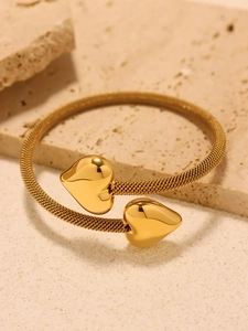 Detail of gold heart open bangle with flexible mesh band on natural stone base