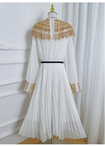 Detail of white chiffon dress showing gold sequin embroidery and pleated long sleeves