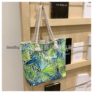 Detail of canvas tote with tropical palm leaf print and thick rope handles on wooden shelf