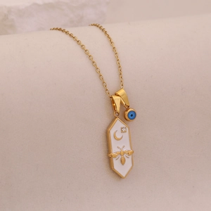 Detailed close-up of a gold hexagonal bee pendant with moon and stars on a white enamel base