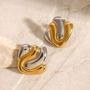 Vue détaillée de boucles d'oreilles vagues bicolores or et argent sur fond de pierre