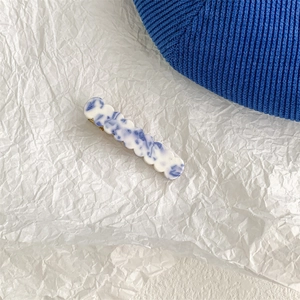 Macro detail of wave-edge hair clip with blue and white marble pattern texture
