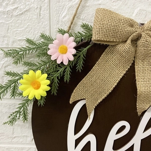 Easter wooden hello door sign featuring burlap bow and artificial daisies on white brick wall