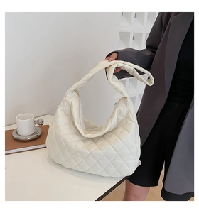 Quilted tote bag in cream white padded fabric styled on a white table with coffee