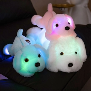 Colorful LED glowing plush puppy toys in pink blue and white on a leather sofa