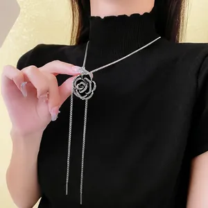 Elegant silver rose necklace with black enamel inlay and crystals on a black sweater