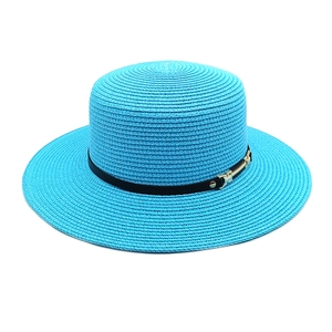 Détail du chapeau de paille turquoise avec ruban noir et boucle dorée élégante