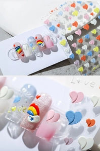 Detail of 3D embossed nail stickers featuring colorful hearts and rainbow Love designs