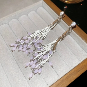 Gros plan de boucles d'oreilles pampilles en argent avec perles lilas sur velours