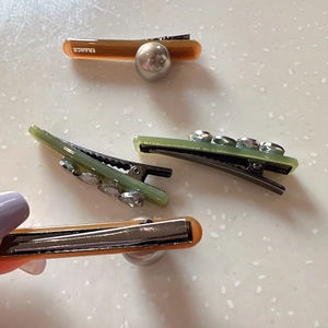 Detailed view of hair clips with rhinestones and acrylic pearls in brown and green tones