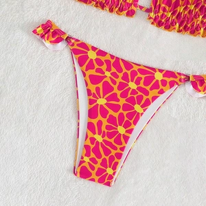 Detail of floral bikini bottom with metal side rings and ruffled edges on white fur background