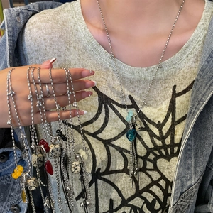 Detail of silver beaded necklace featuring heart crystals and stone sphere tassels