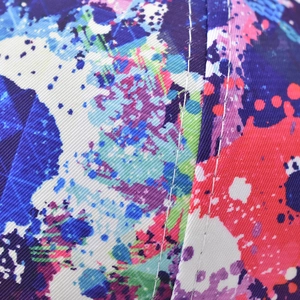 Macro detail of colorful spray-paint graffiti pattern and white contrast stitching on twill fabric