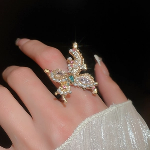 Close-up of vintage gold butterfly ring with inlaid pearls and sparkling colorful gemstones