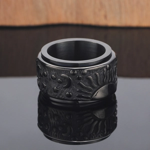 Detail of a rotating stainless steel ring with embossed sun moon and star patterns