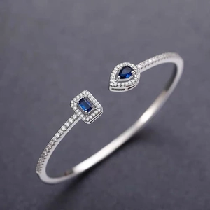 Macro shot of silver open bangle with blue teardrop and rectangle zircon stones