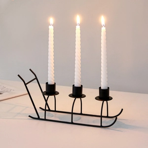 Black metal sled candle holder with three white spiral candles for Christmas decor