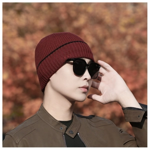 Outdoor model shot of men's dark red knit beanie with black stripes and warm inner lining