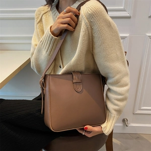 Minimalist brown leather crossbody bucket bag shown on model with chic autumn styling