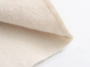 Detailed close-up of soft cream sherpa fleece fabric texture with precise stitching detail