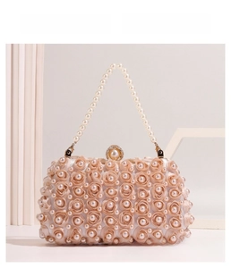 Close-up of champagne satin evening bag featuring fabric roses and pearl accents