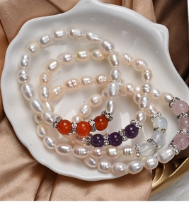 Detail of freshwater pearl bracelets with colorful gemstones and rhinestone spacers in a shell bowl