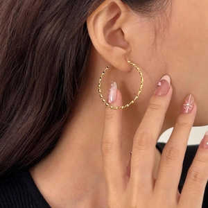 Polished golden twisted rope hoop earrings for women in a minimalist fashion style
