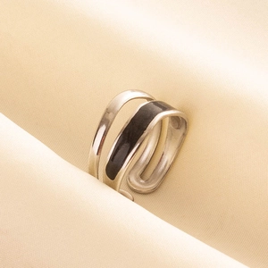 Detail of silver 304 stainless steel ring with black enamel band on soft beige fabric