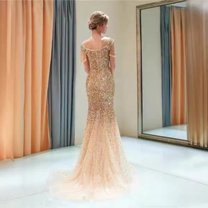 Abito da sera a sirena con paillettes oro champagne, senza maniche con frange e strascico