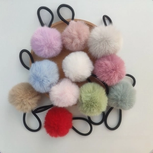 Detailed view of assorted macaron colored faux fur pom pom hair ties on a wooden tray