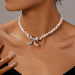 Dettaglio macro di un girocollo di perle con un pendente a fiocco scintillante con diamanti