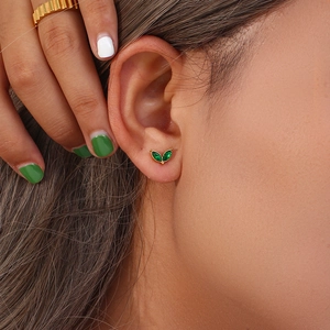 Macro view of gold plated flower stud earring with green marquise zircon on ear