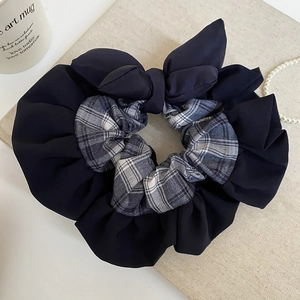 Detail of grey plaid and black fabric scrunchie with large bow on a vintage background