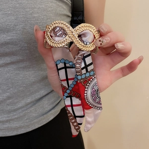 Detail of gold metal cuff bracelet wrapped with silk fabric scarf featuring geometric patterns