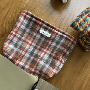 Macro shot of retro plaid wool fabric texture and woven brand label on cosmetic bag