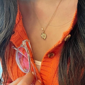 Detailed view of vintage gold portrait coin necklace with pearl detail on silver chain