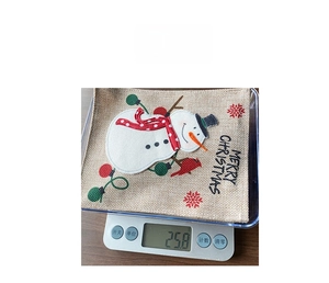 Weight measurement of linen Christmas gift bag featuring snowman embroidery and Merry Christmas text