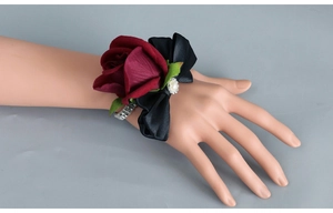 Detail of burgundy rose wrist corsage with black satin bow and rhinestone elastic band