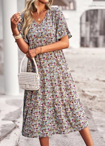 Detail of V-neck short sleeve dress with blue floral print and white woven handbag