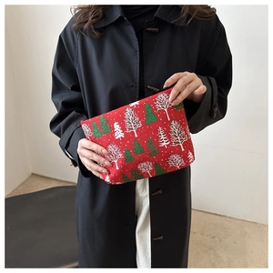 Detailansicht der roten Kosmetiktasche mit Weihnachtsbaummuster in der Hand