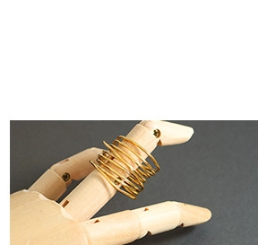 Detail of a handmade gold multilayer spiral ring showcased on a wooden hand model