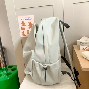 Minimalist light grey green casual backpack with pleated design shown on a white chair