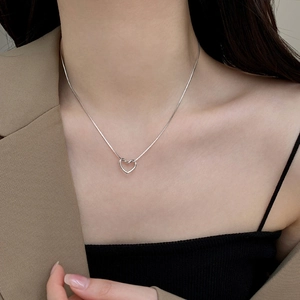 Gros plan du collier avec pendentif cœur argenté minimaliste porté par un mannequin