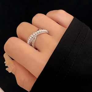 Close-up of zircon pearl crisscross ring showing delicate silver plating on finger