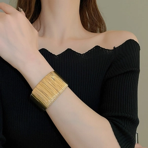 Close-up of wide gold twisted cuff bracelet with horizontal brushed metal texture