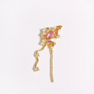 Detailed macro shot of golden butterfly earring with pink gemstones and long crystal tassels