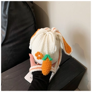 Close-up of handmade white crochet rabbit bucket bag with orange carrot and floral detail