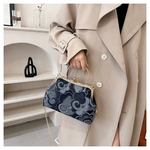 Close-up of denim frame bag featuring vintage cloud patterns and gold chain strap