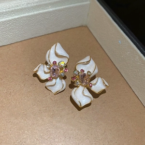 Macro shot of 3D floral earrings with white enamel petals and multicolor gemstone center